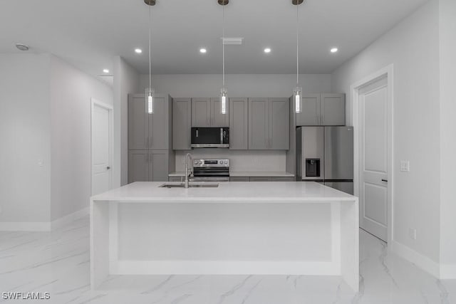 kitchen featuring gray cabinetry, a center island with sink, hanging light fixtures, and appliances with stainless steel finishes