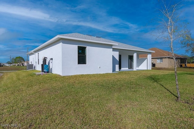 rear view of house with a lawn and central AC