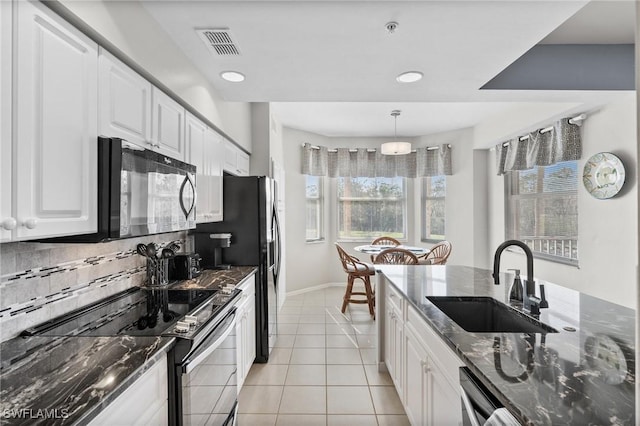 kitchen with electric range, tasteful backsplash, dark stone countertops, and sink