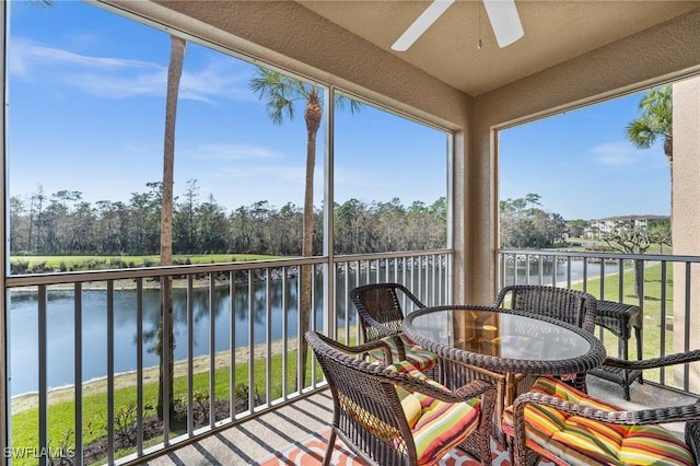 sunroom / solarium with ceiling fan and a water view