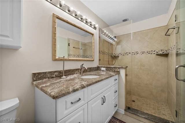 bathroom with tile patterned flooring, toilet, vanity, and walk in shower