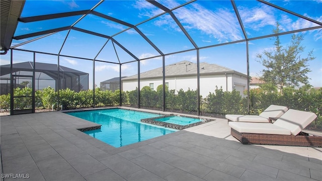 view of pool with glass enclosure, a pool with connected hot tub, and a patio area