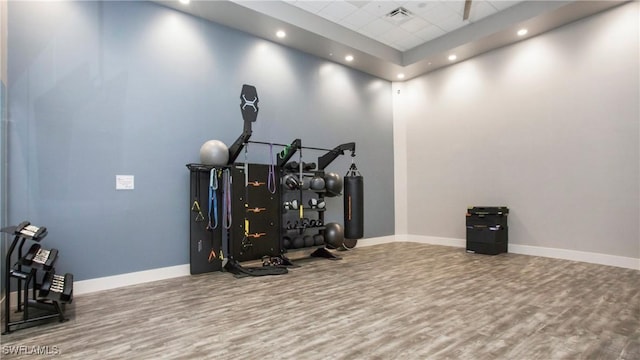 workout room with wood finished floors, visible vents, and baseboards