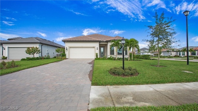 mediterranean / spanish home with a front lawn, a tiled roof, stucco siding, decorative driveway, and a garage