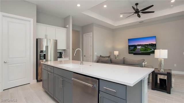 kitchen with gray cabinets, stainless steel appliances, light countertops, and a sink