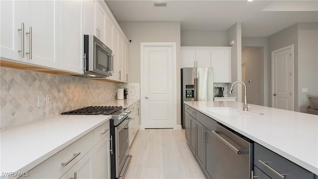 kitchen featuring visible vents, a sink, stainless steel appliances, light countertops, and white cabinets