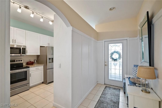 interior space with plenty of natural light, light tile patterned flooring, white cabinetry, and stainless steel appliances