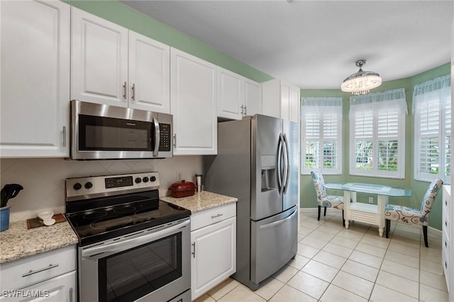 kitchen with light stone countertops, light tile patterned floors, white cabinetry, and appliances with stainless steel finishes