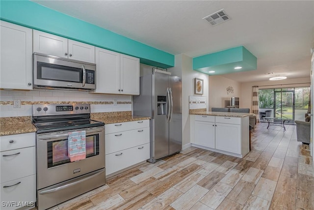 kitchen with white cabinetry, light stone countertops, light hardwood / wood-style flooring, kitchen peninsula, and appliances with stainless steel finishes