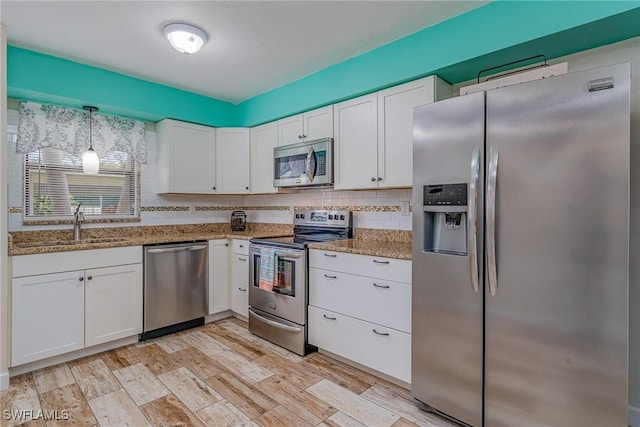 kitchen with white cabinets, appliances with stainless steel finishes, and light hardwood / wood-style flooring