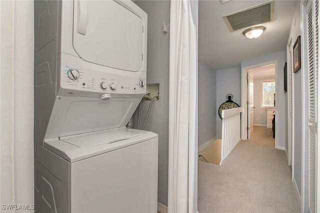 laundry room with light carpet and stacked washer / drying machine