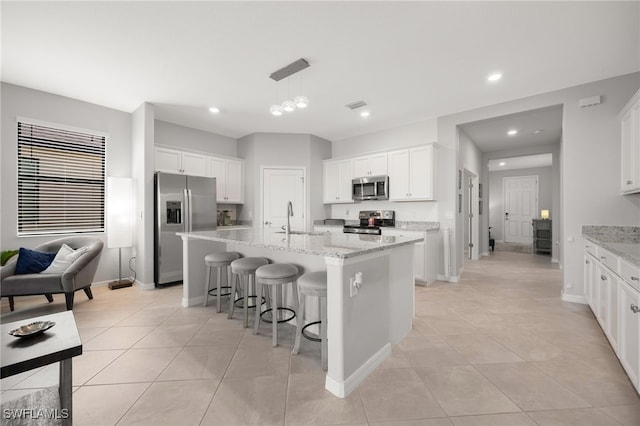 kitchen featuring stainless steel appliances, white cabinetry, and a kitchen island with sink