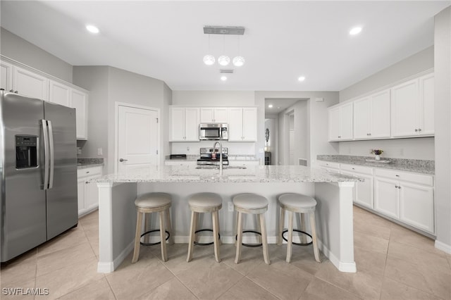 kitchen with white cabinets, stainless steel appliances, and an island with sink