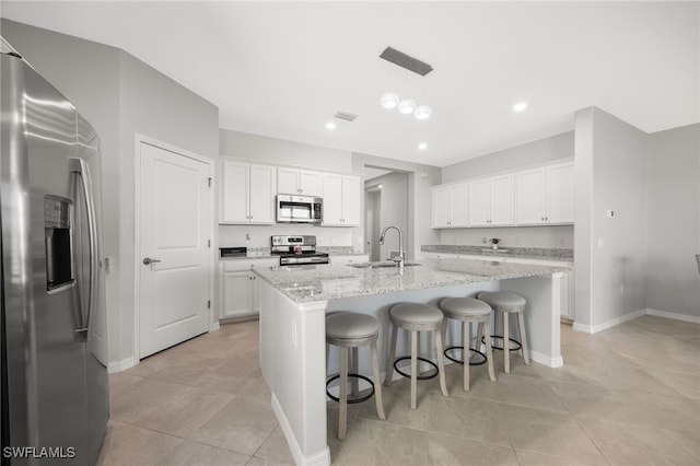 kitchen with pendant lighting, a center island with sink, sink, white cabinetry, and stainless steel appliances