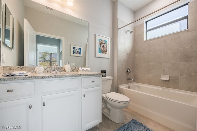 full bathroom with tile patterned flooring, tiled shower / bath combo, toilet, and vanity