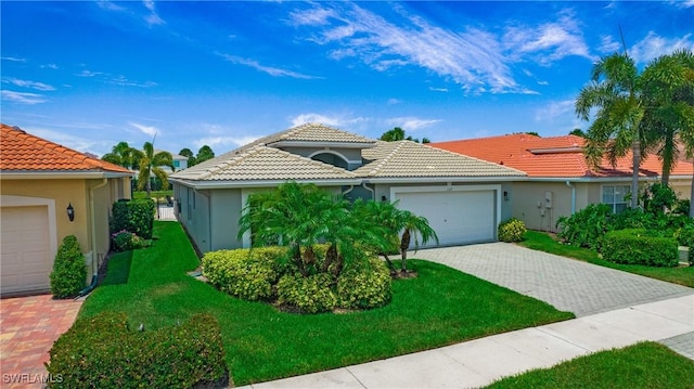 view of front of property featuring decorative driveway, a tile roof, stucco siding, a front yard, and a garage