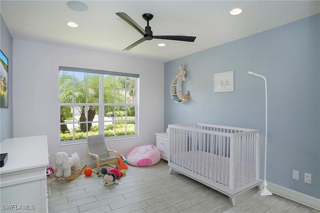 bedroom with a crib, light wood-style flooring, ceiling fan, and recessed lighting