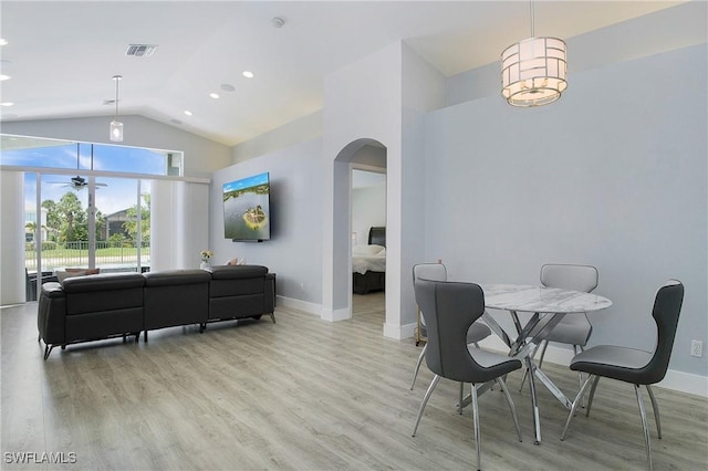 dining area with arched walkways, baseboards, visible vents, and light wood finished floors