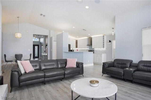 living area featuring lofted ceiling, recessed lighting, visible vents, and light wood-style floors