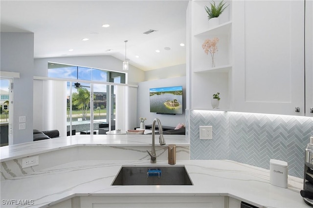 kitchen with white cabinets, light stone countertops, open shelves, and a sink