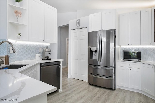 kitchen with appliances with stainless steel finishes, white cabinetry, and a sink