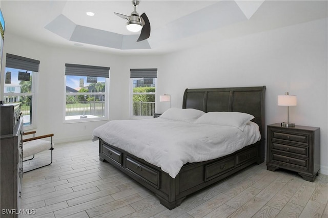 bedroom with a tray ceiling, recessed lighting, a ceiling fan, light wood-type flooring, and baseboards