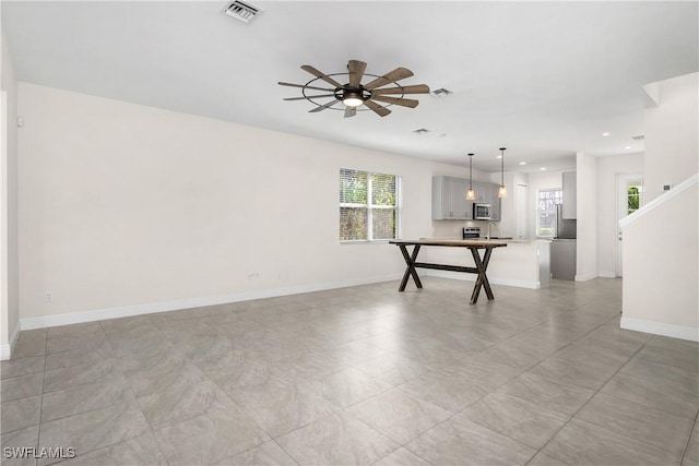 unfurnished room with ceiling fan and a healthy amount of sunlight