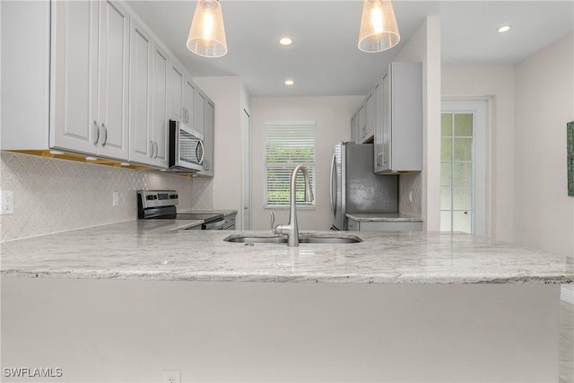 kitchen with stainless steel appliances, white cabinetry, hanging light fixtures, and sink