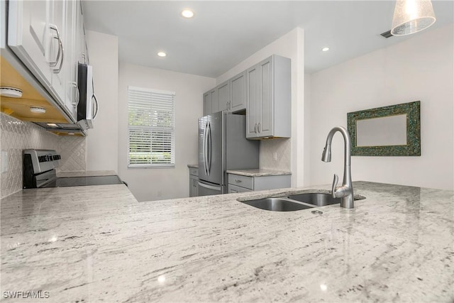 kitchen featuring stove, sink, decorative backsplash, gray cabinets, and stainless steel refrigerator