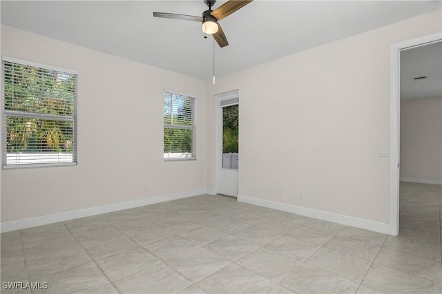 empty room with ceiling fan and light tile patterned floors