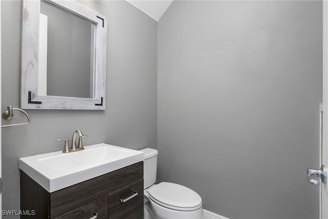 bathroom with vanity, toilet, and vaulted ceiling