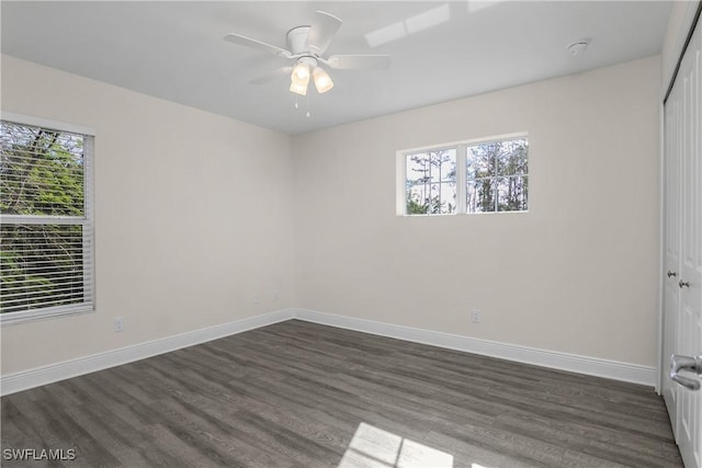 spare room featuring ceiling fan, dark wood-type flooring, and a healthy amount of sunlight