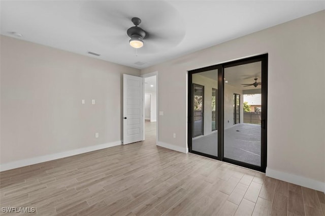 unfurnished room with a ceiling fan, visible vents, baseboards, and wood finished floors