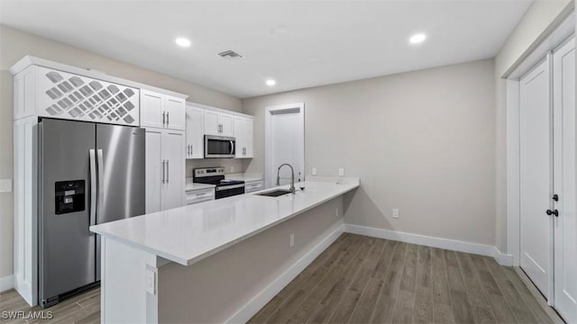 kitchen with white cabinets, kitchen peninsula, sink, and appliances with stainless steel finishes