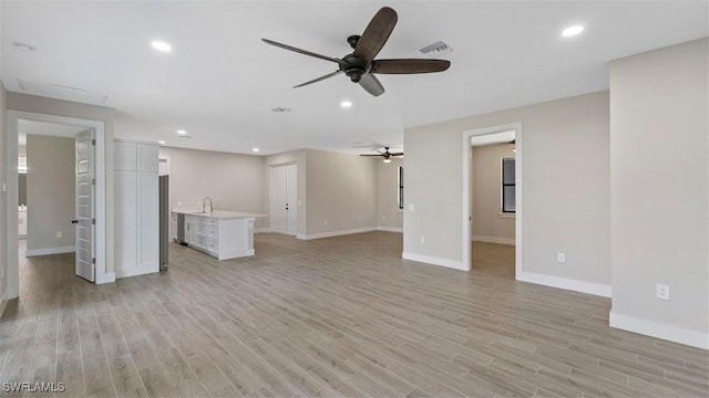 unfurnished living room featuring ceiling fan, sink, and light hardwood / wood-style flooring