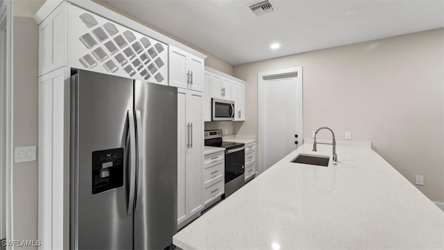 kitchen featuring white cabinetry, sink, light stone countertops, kitchen peninsula, and appliances with stainless steel finishes