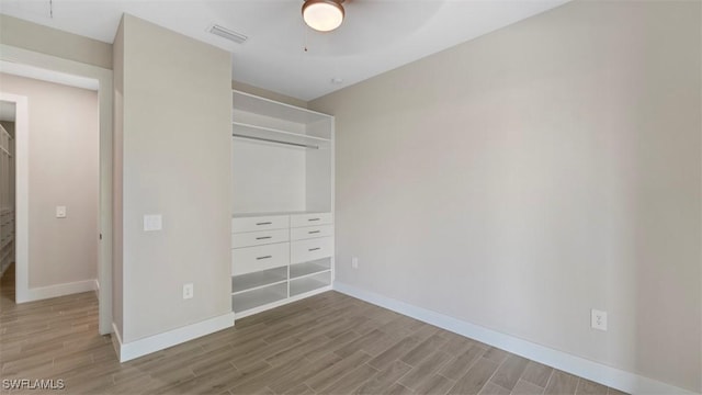 unfurnished bedroom featuring a closet, visible vents, baseboards, and wood finished floors