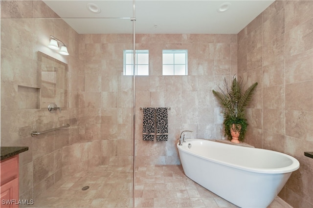 bathroom with vanity, separate shower and tub, and tile walls