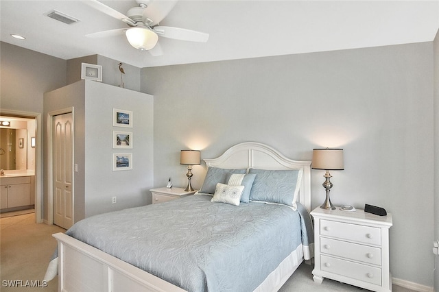 bedroom with ceiling fan, light colored carpet, and connected bathroom