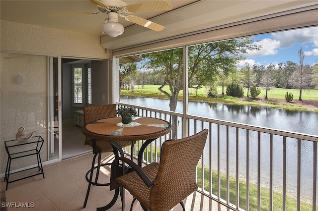 sunroom featuring ceiling fan, plenty of natural light, and a water view