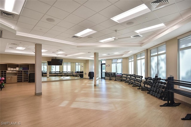 exercise room featuring light wood-type flooring, a raised ceiling, and a drop ceiling