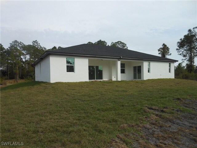 back of property with a lawn and stucco siding