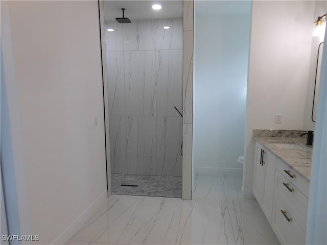 bathroom with vanity, toilet, and tiled shower