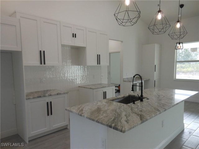 kitchen with pendant lighting, white cabinetry, a center island with sink, and a sink