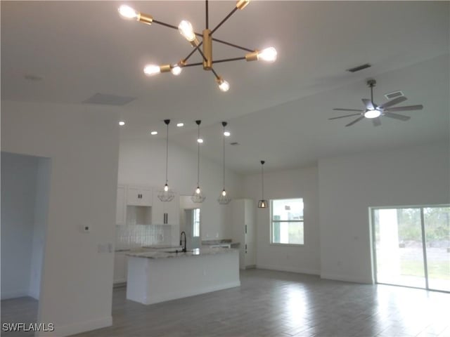 kitchen featuring sink, high vaulted ceiling, a center island with sink, pendant lighting, and white cabinets