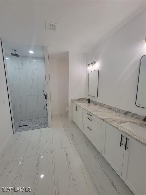 bathroom with tiled shower, vanity, and toilet