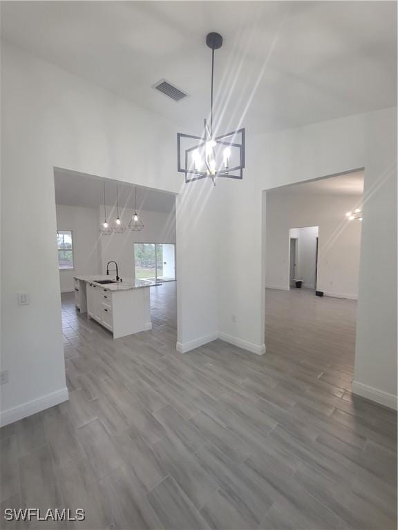 unfurnished dining area featuring sink, hardwood / wood-style floors, and a notable chandelier