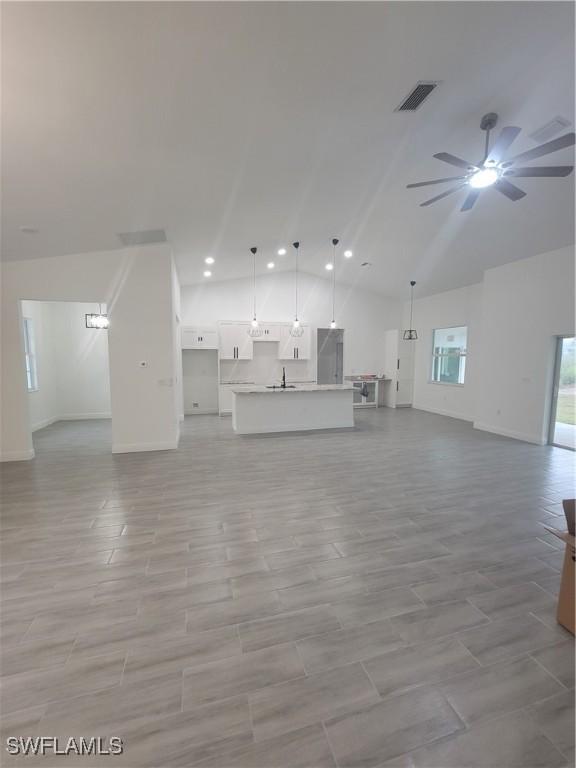 unfurnished living room featuring sink, high vaulted ceiling, and ceiling fan