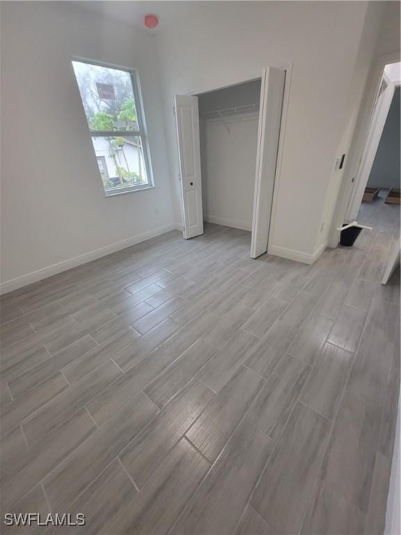 unfurnished bedroom featuring wood tiled floor, baseboards, and a closet