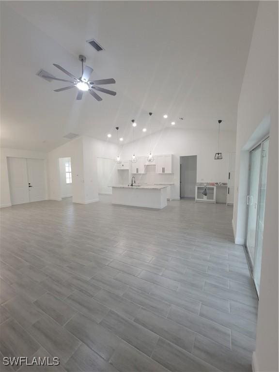 unfurnished living room featuring high vaulted ceiling, sink, and ceiling fan